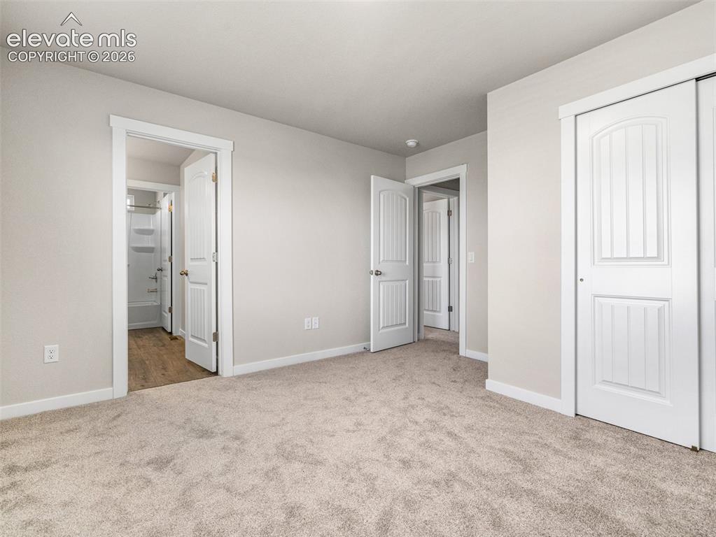 Image 8 of 30: Neutral-toned carpeting, white trim, and white paneled doors