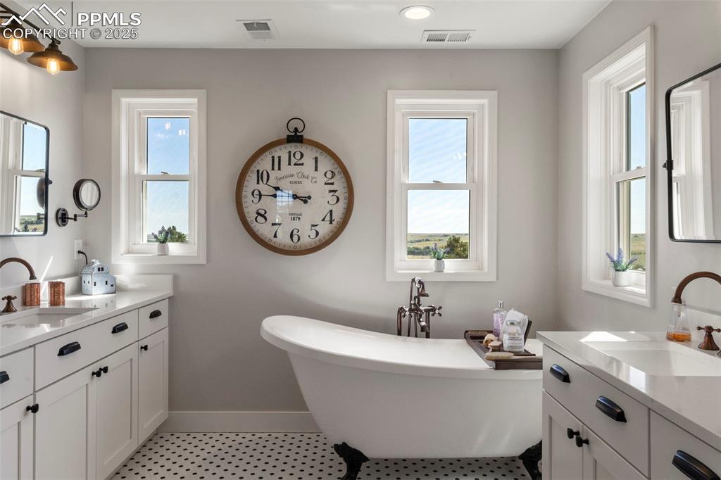 Image 22 of 50: Updated and stunning primary bath with claw foot soaking tub, double vaniti