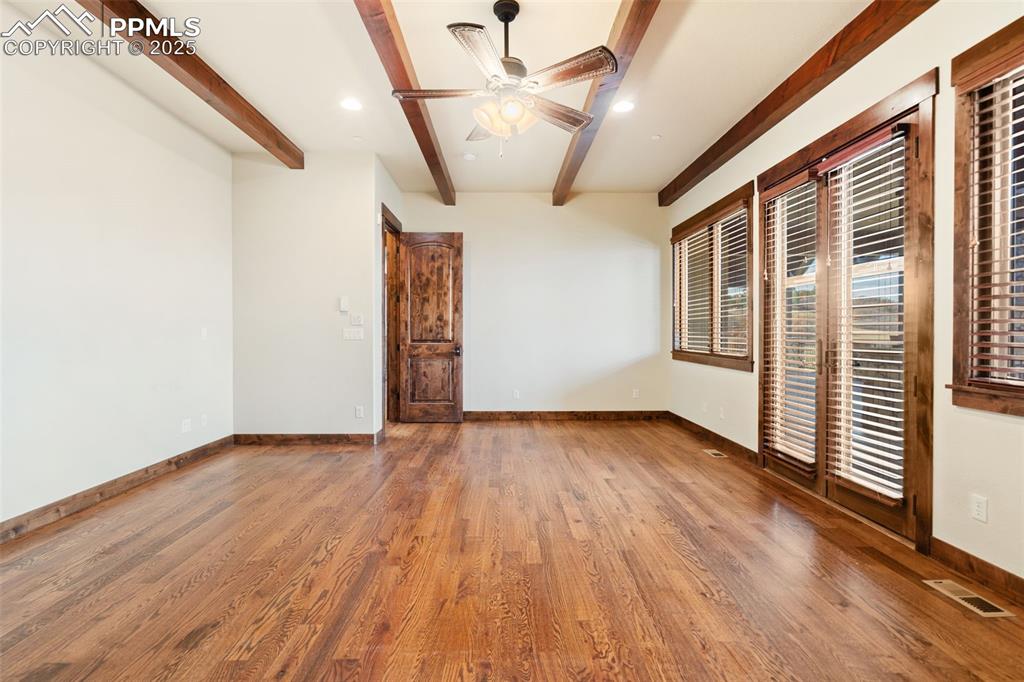 Image 20 of 50: Main level primary bedroom features a beamed ceiling and access to the uppe
