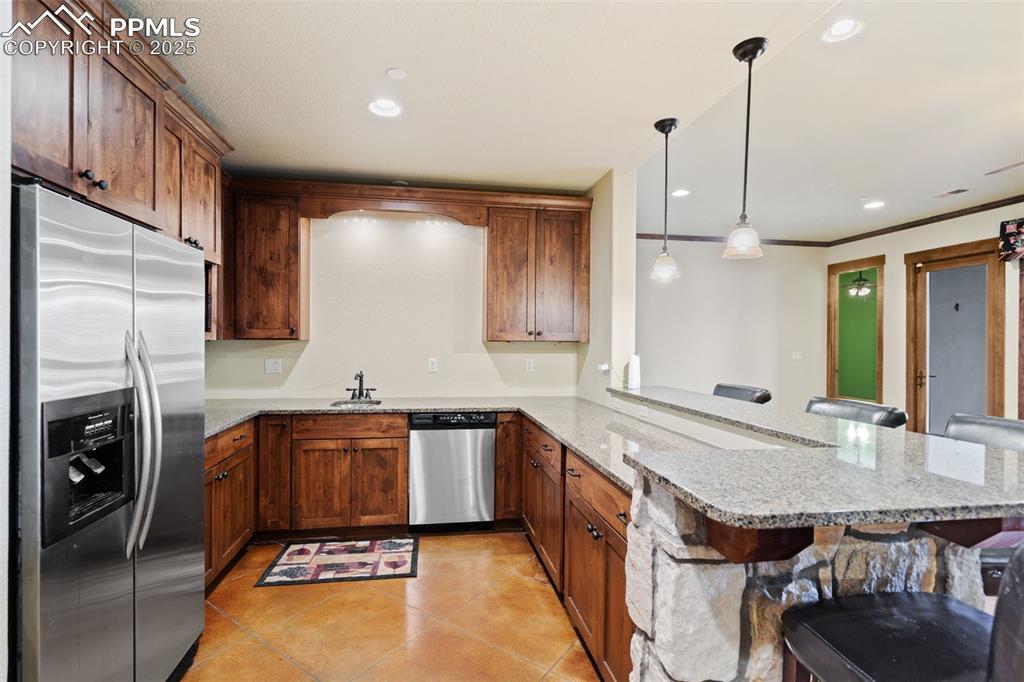 Image 35 of 50: Basement family room boasts a kitchen with granite counters, full size frid