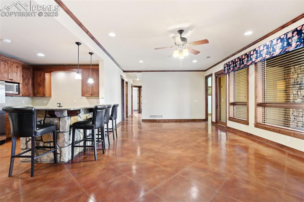 Image 36 of 50: The spacious basement family room with stained, stamped concrete flooring p