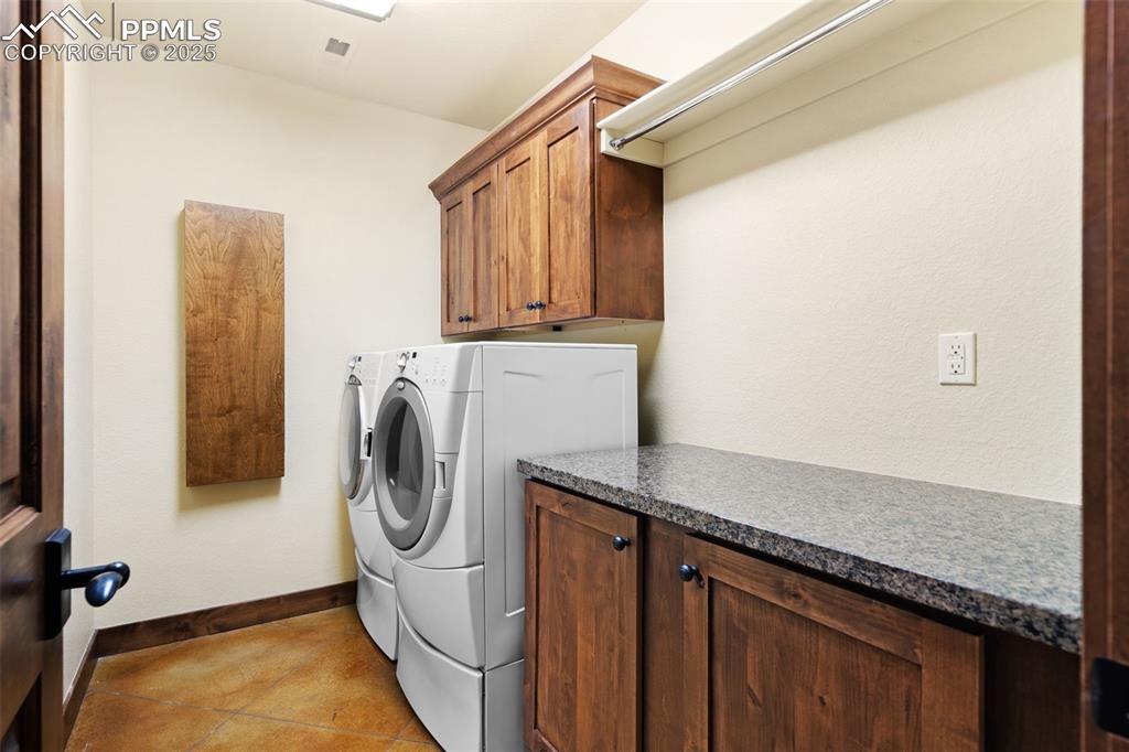 Image 44 of 50: Basement laundry room includes storage cabinets, a granite folding counter,