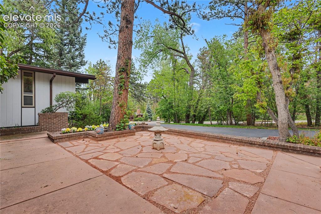 Image 10 of 50: Expansive flagstone patio with a central stone lantern, bordered by brick p