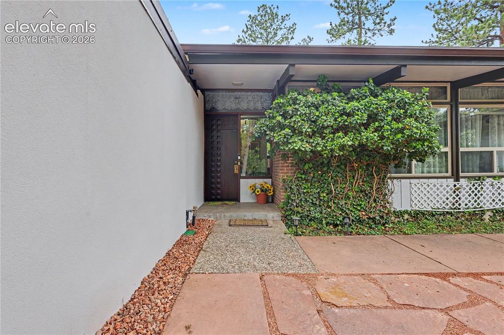 Image 11 of 50: Mid-century modern facade featuring a textured stucco wall and flagstone pa