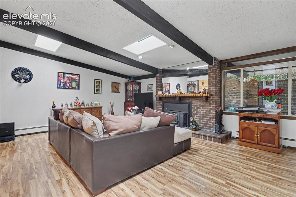Image 13 of 50: Living area featuring wood-finish flooring and exposed ceiling beams