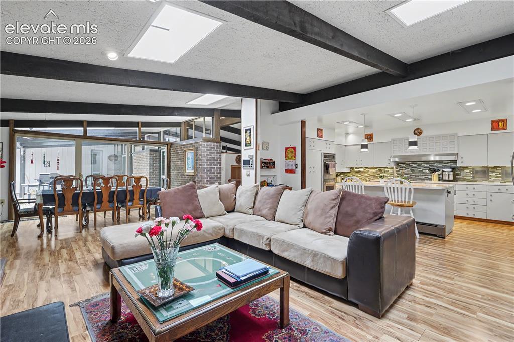 Image 14 of 50: Open-concept living space featuring wood-finish flooring, exposed beams, an