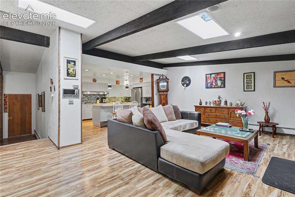 Image 15 of 50: Living area featuring wood-finish flooring, exposed ceiling beams, and rece