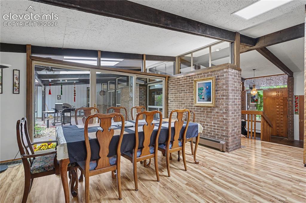Image 16 of 50: Dining area featuring wood-finish flooring, exposed ceiling beams, and a br