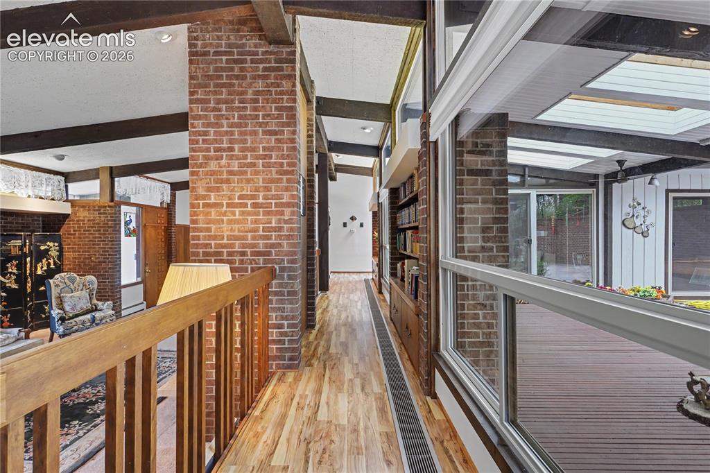 Image 21 of 50: Interior hallway with wood-finish flooring, exposed brick columns, built-in