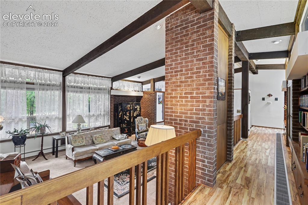 Image 22 of 50: Open-concept living area with exposed beam ceilings, extensive natural ligh