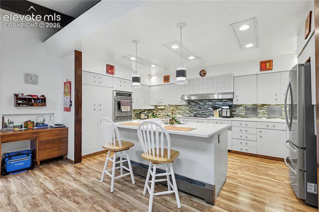 Image 24 of 50: Bright kitchen featuring white cabinetry, built-in stainless steel applianc