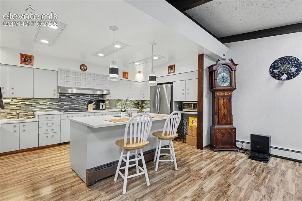 Image 25 of 50: Modern kitchen featuring white cabinetry and wood-finish flooring