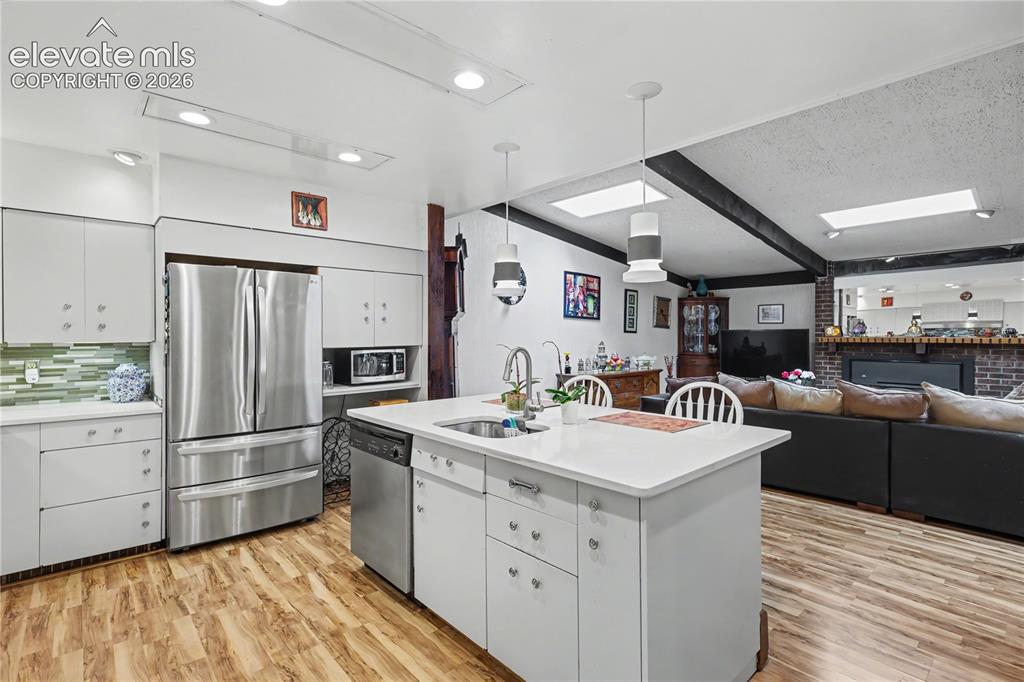 Image 26 of 50: Kitchen featuring a central island with white countertop, stainless steel a