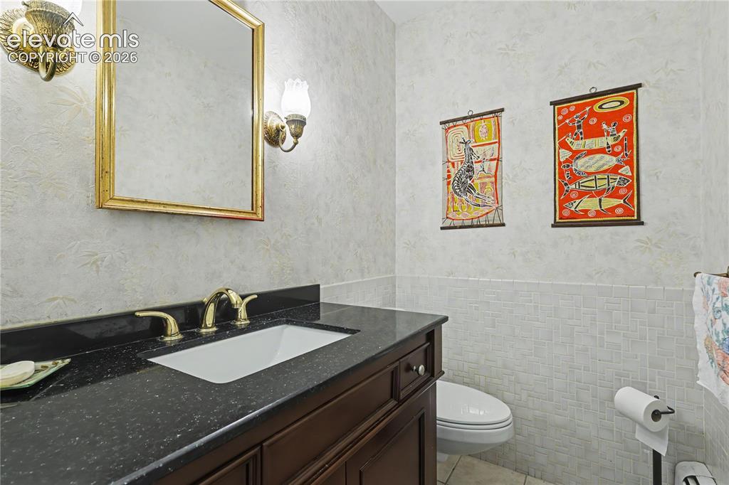 Image 29 of 50: Vanity featuring a dark countertop, an integrated sink with a brass-finish 