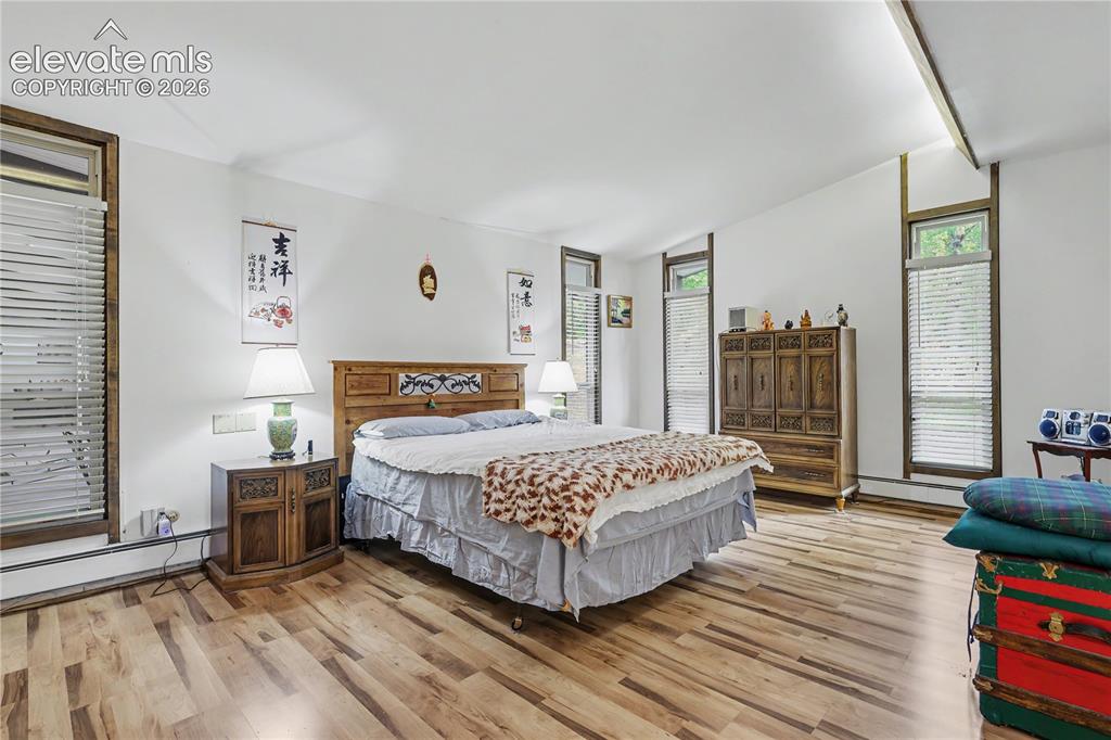 Image 31 of 50: Spacious room featuring wood-finish flooring, a vaulted ceiling, and multip