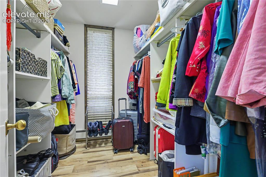 Image 33 of 50: Walk-in closet featuring wood-finish flooring, built-in shelving, hanging r