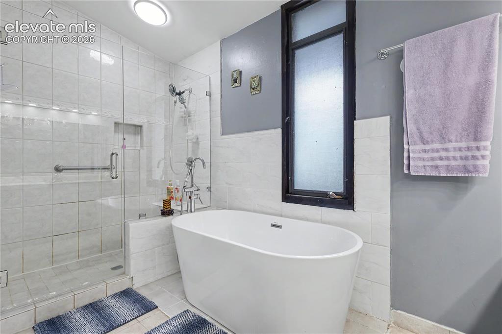 Image 35 of 50: Bathroom featuring a freestanding soaking tub, a frameless glass shower enc