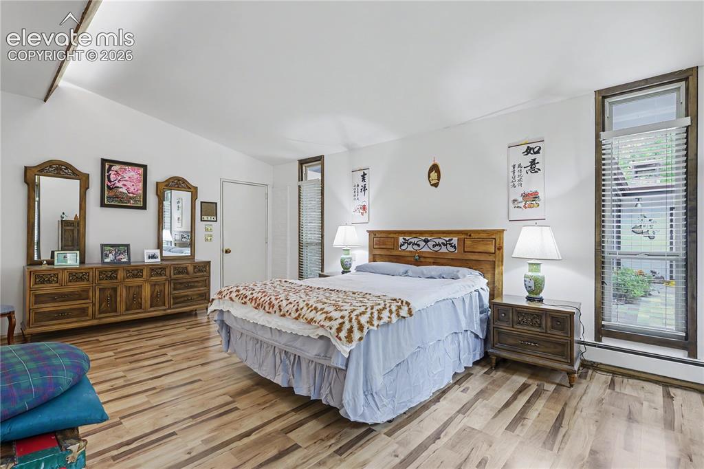 Image 36 of 50: Bright interior space featuring wood-finish flooring, a vaulted ceiling wit