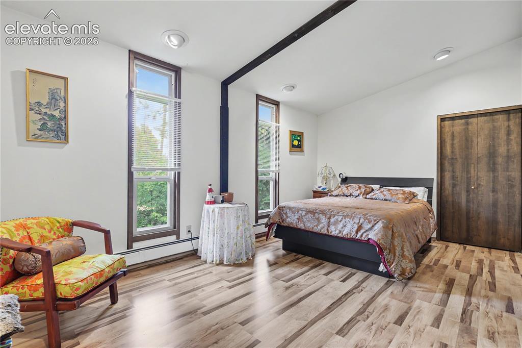 Image 37 of 50: Spacious room featuring light wood-finish flooring, white walls, and a vaul