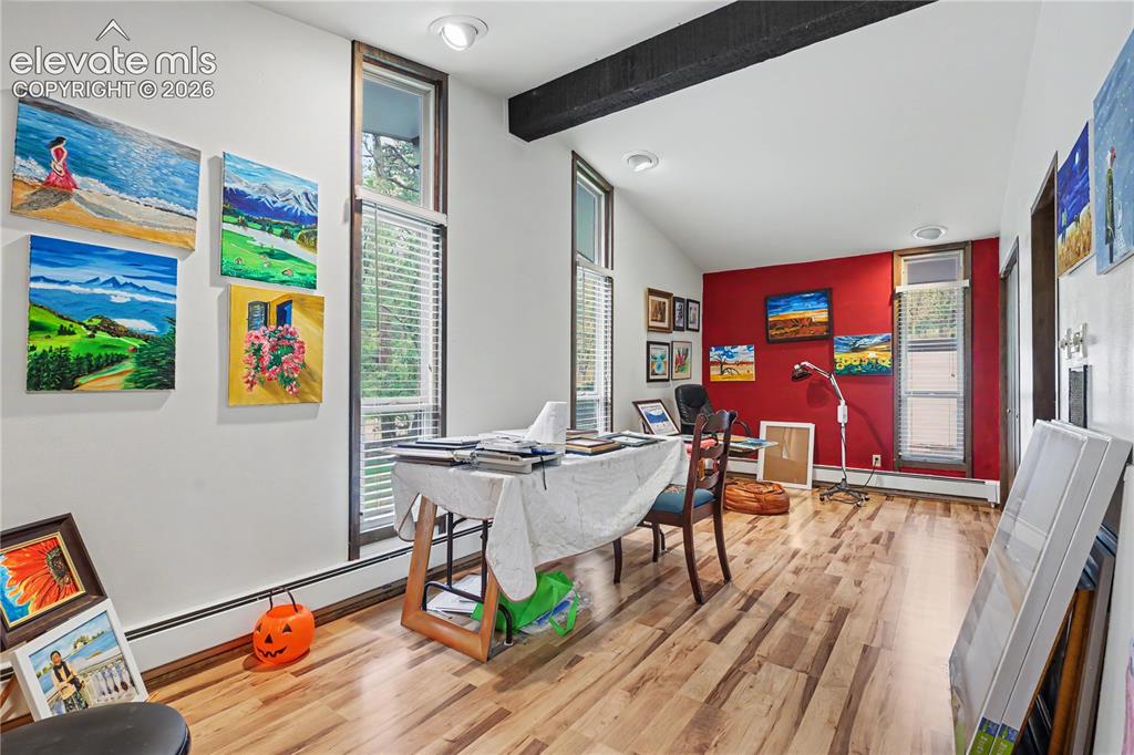Image 38 of 50: Room featuring wood-finish flooring, a vaulted white ceiling with exposed d