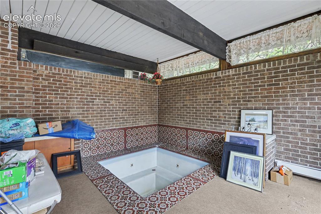Image 46 of 50: Sunken spa tub framed by decorative tiled surround