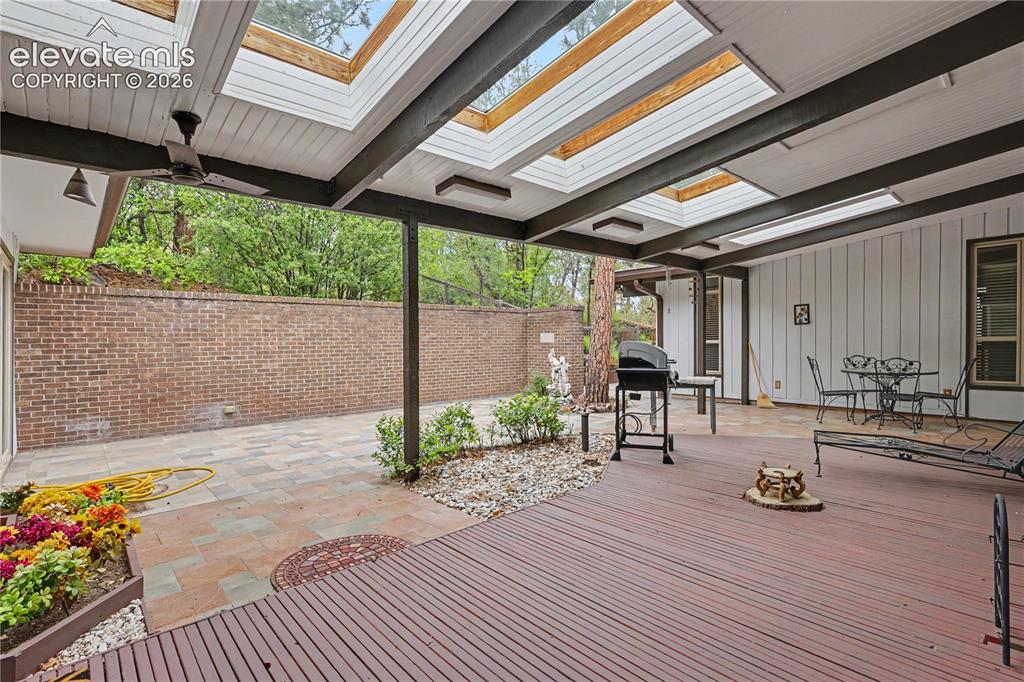 Image 48 of 50: Covered outdoor living area featuring a wood-finish deck, skylights, and a 