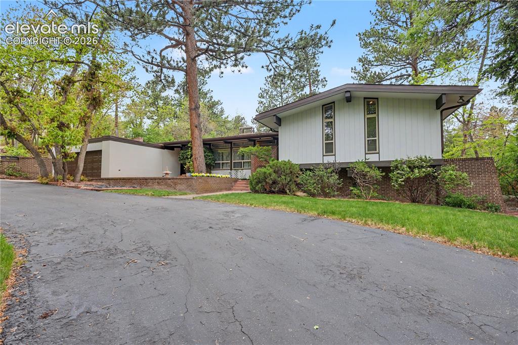 Image 8 of 50: Mid-century modern residence featuring white vertical siding, a low-slope r