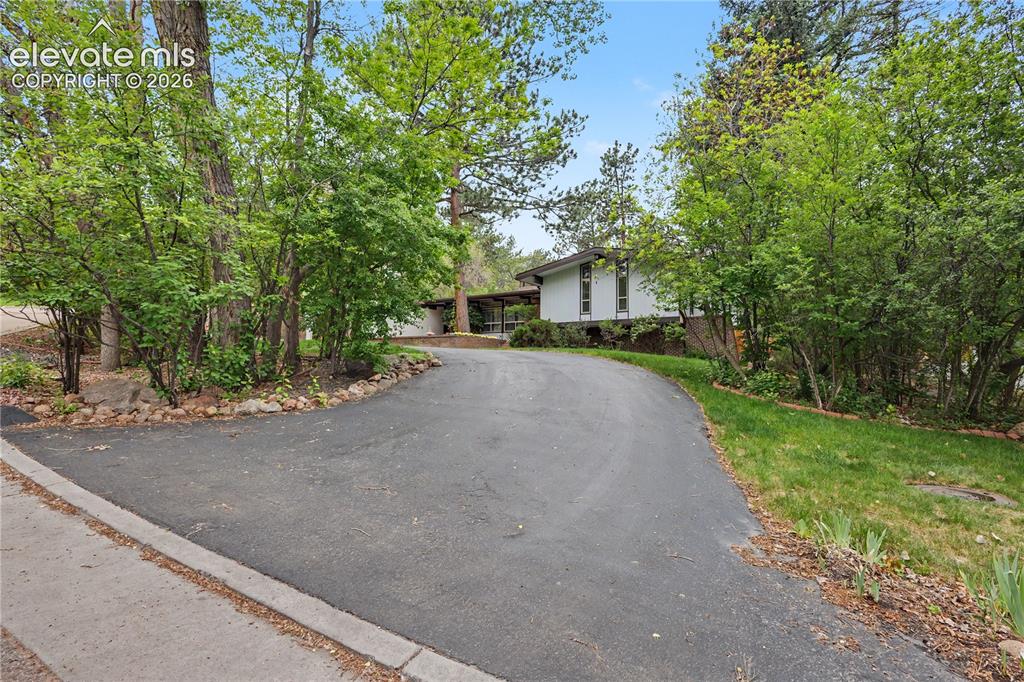 Image 9 of 50: Curved asphalt driveway leading to a contemporary residence