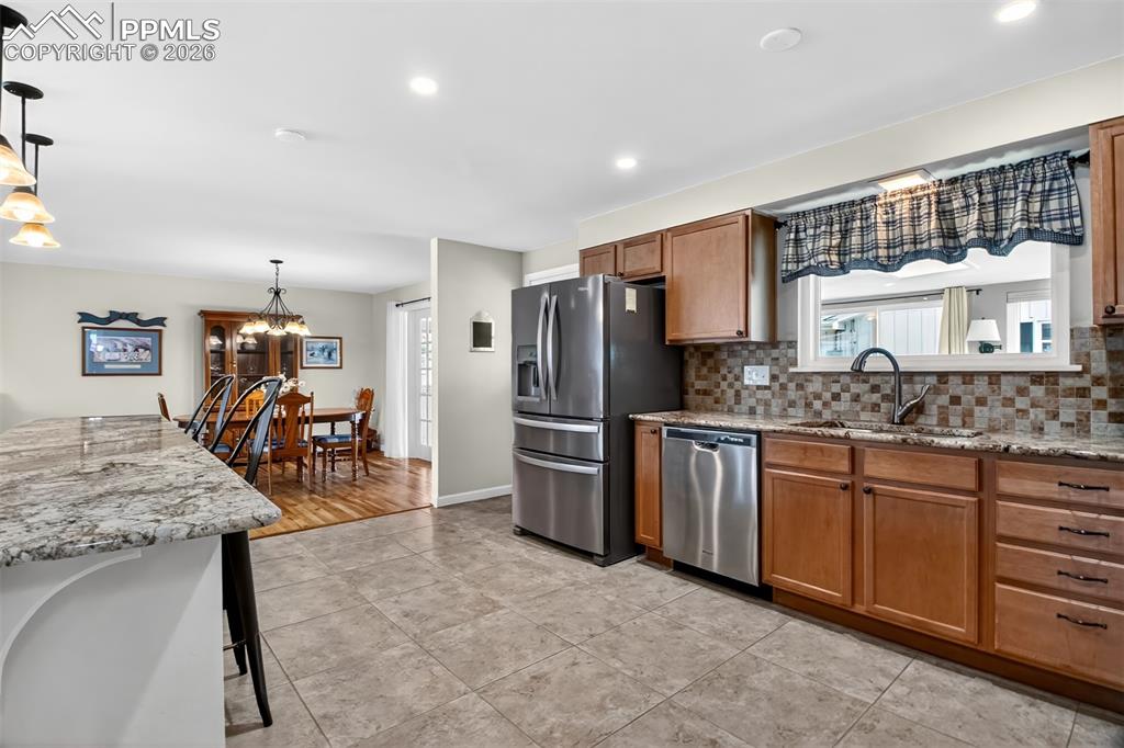 Image 12 of 39: Granite Counters, Tile Backsplash, Pendant Lights Above The Breakfast Bar