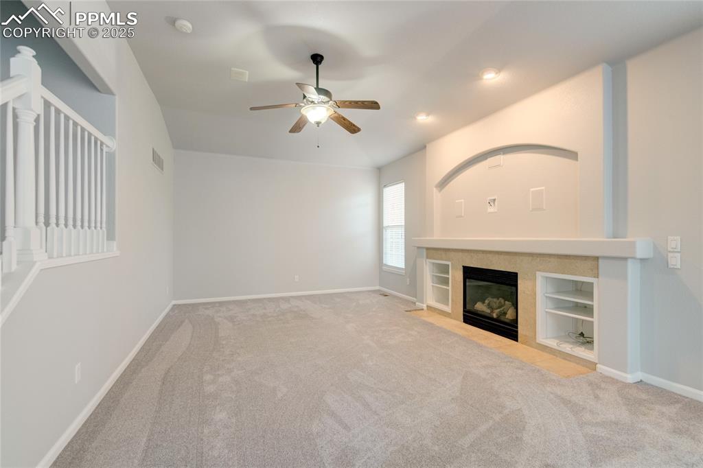 Image 5 of 23: Unfurnished living room featuring a ceiling fan, carpet floors, a tiled fir