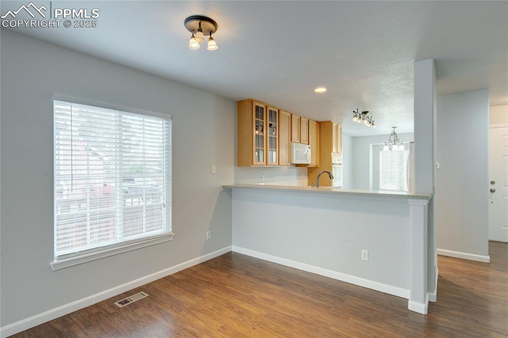 Image 6 of 23: Kitchen with white appliances, glass insert cabinets, dark wood-style floor