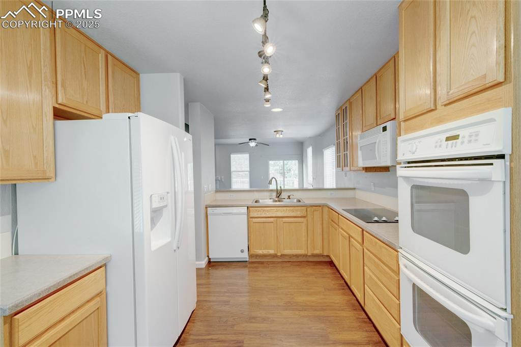 Image 8 of 23: Kitchen with white appliances, light brown cabinets, light wood-style floor