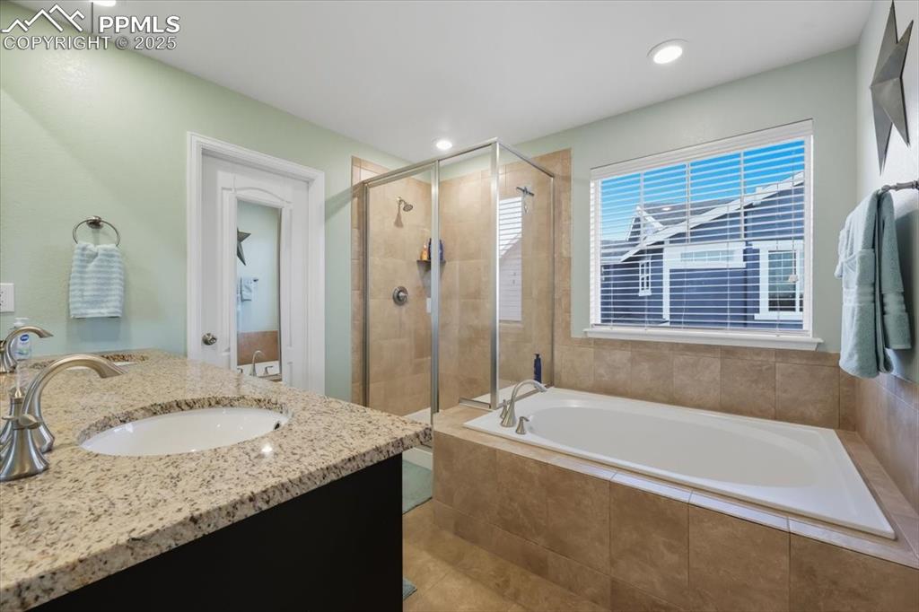Image 11 of 35: Bathroom with a bath, a stall shower, double vanity, and recessed lighting