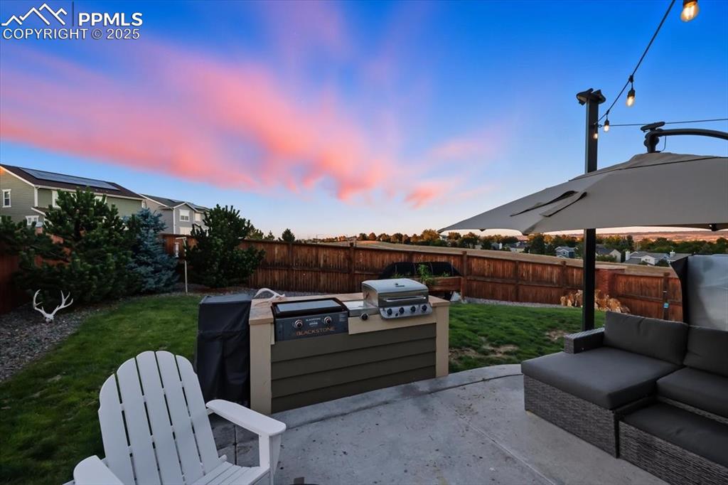 Image 23 of 35: Fenced backyard with a patio, grilling area, and an outdoor living space