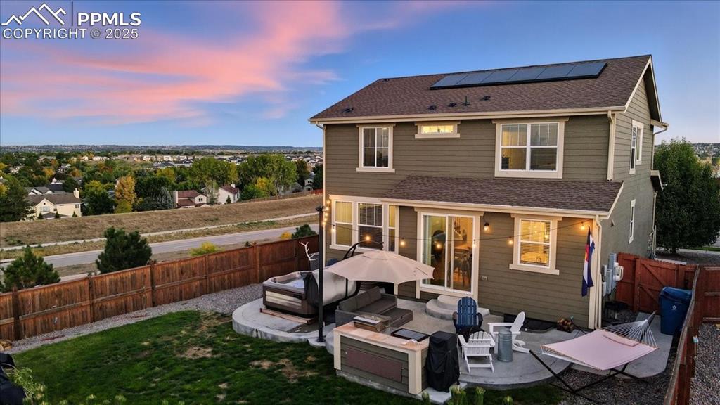 Image 26 of 35: Back of house featuring roof with shingles, solar panels, a patio area, a f