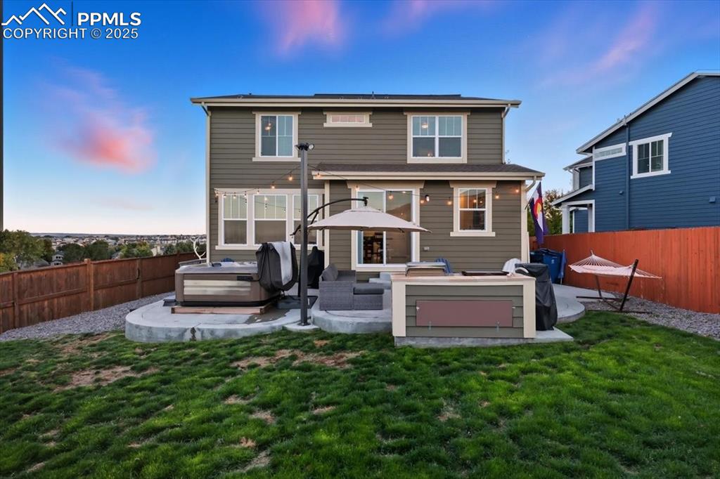 Image 31 of 35: Back of house at dusk featuring a hot tub, a fenced backyard, a patio area,