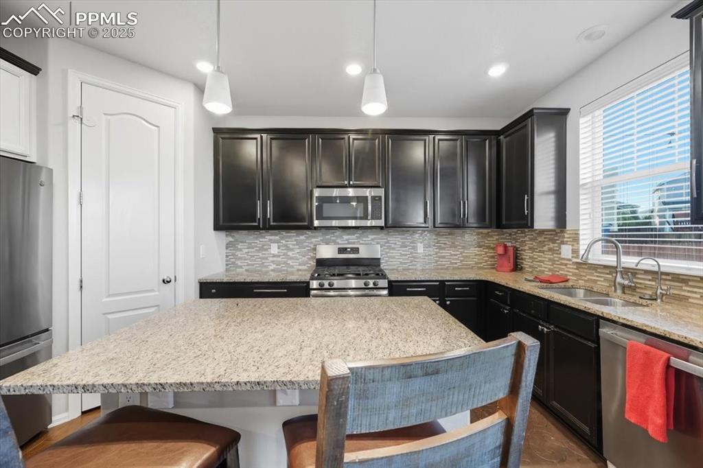 Image 8 of 35: Kitchen featuring light stone countertops, appliances with stainless steel