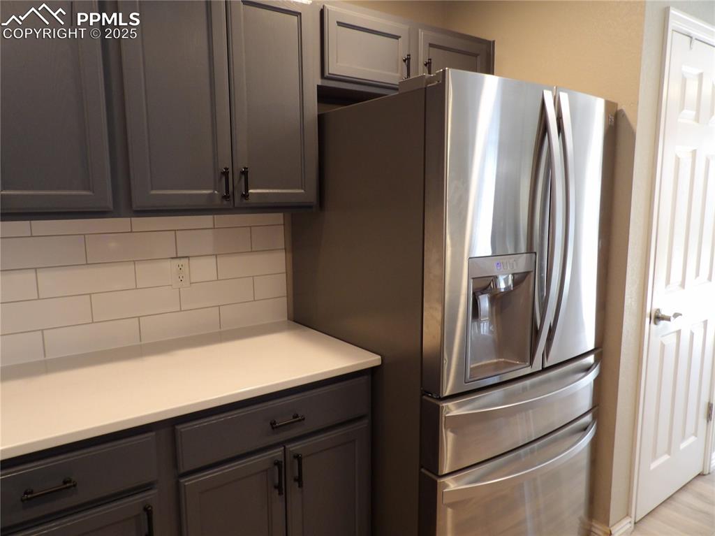 Image 10 of 23: Kitchen featuring stainless steel fridge with ice dispenser, decorative bac