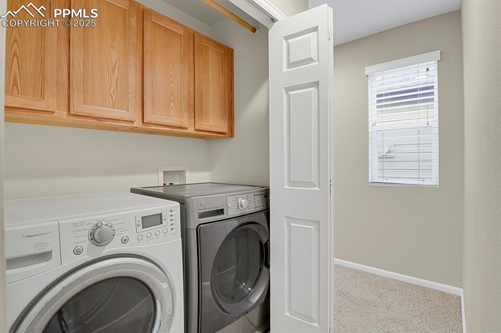 Image 24 of 26: Washroom featuring cabinet space, washing machine and dryer, and carpet flo