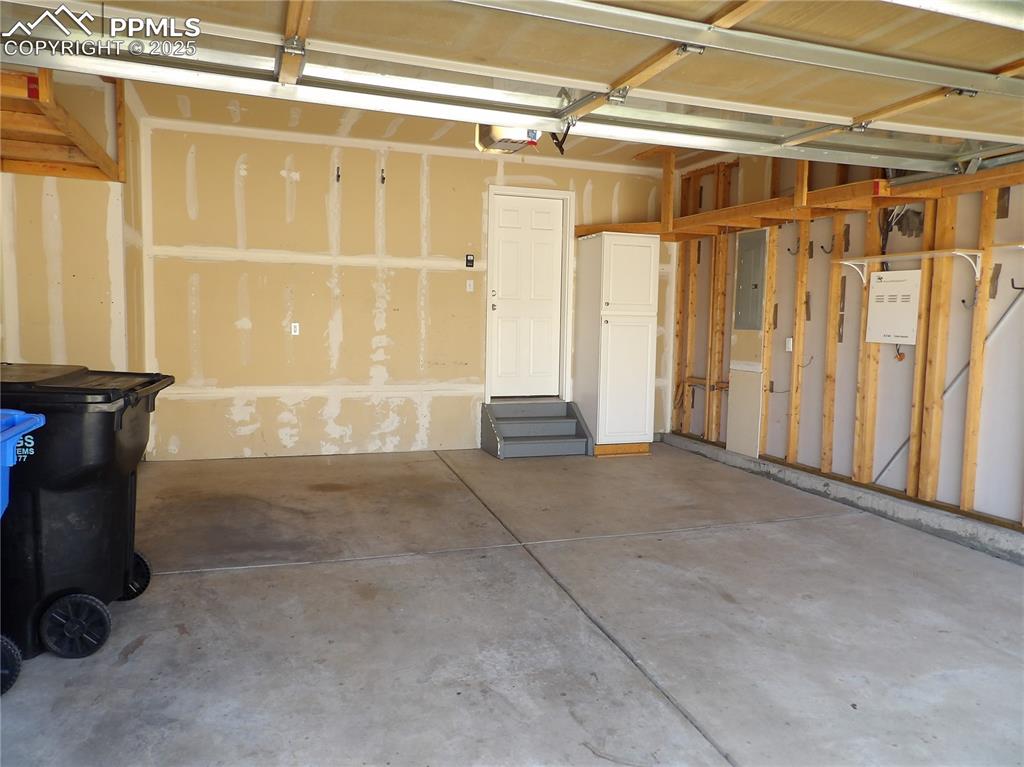 Image 3 of 23: Garage featuring electric panel and a garage door opener