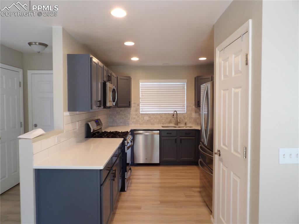 Image 6 of 23: Kitchen featuring stainless steel appliances, backsplash, light wood-style