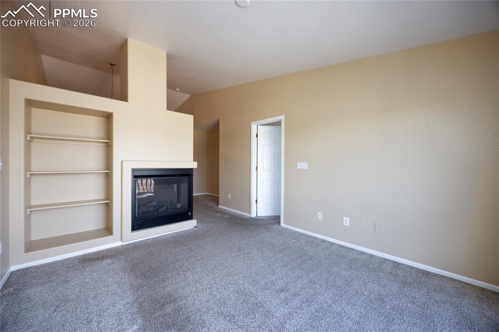 Image 10 of 25: Spacious living area featuring a built-in fireplace with a black insert, in