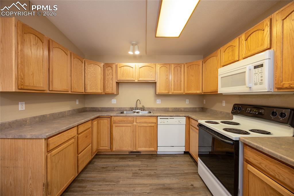 Image 11 of 25: U-shaped kitchen featuring wood-finish cabinetry, solid surface countertops