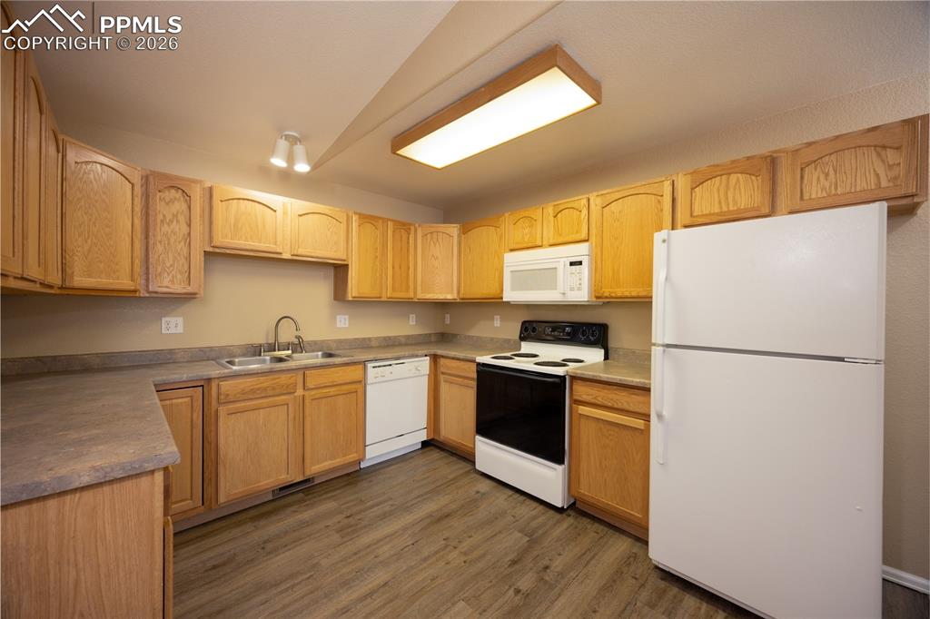 Image 12 of 25: Kitchen featuring light wood cabinetry, gray-toned countertops, and wood-fi