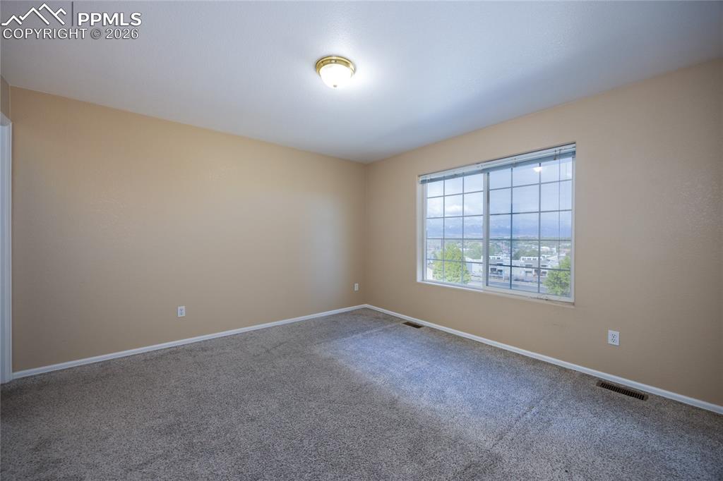 Image 15 of 25: Spacious room featuring neutral wall tones and plush grey carpeting