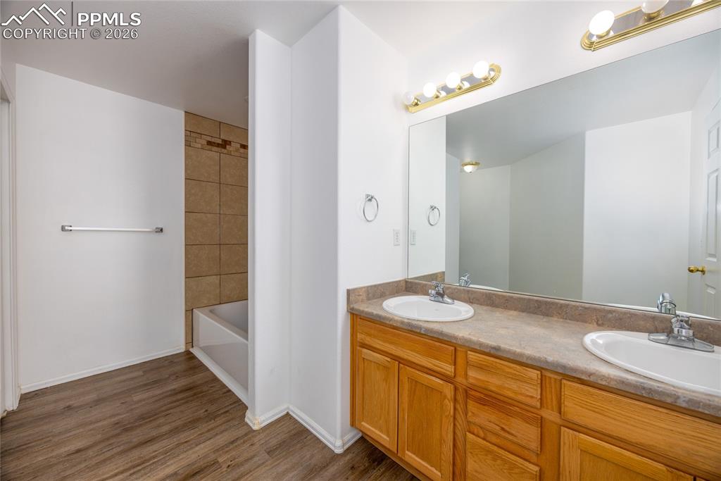 Image 17 of 25: Bathroom featuring a dual vanity with oak cabinetry, a large wall-mounted m