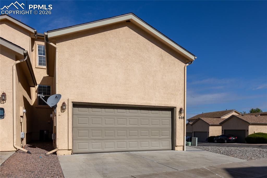 Image 4 of 25: Stucco exterior with a paneled garage door and a concrete driveway