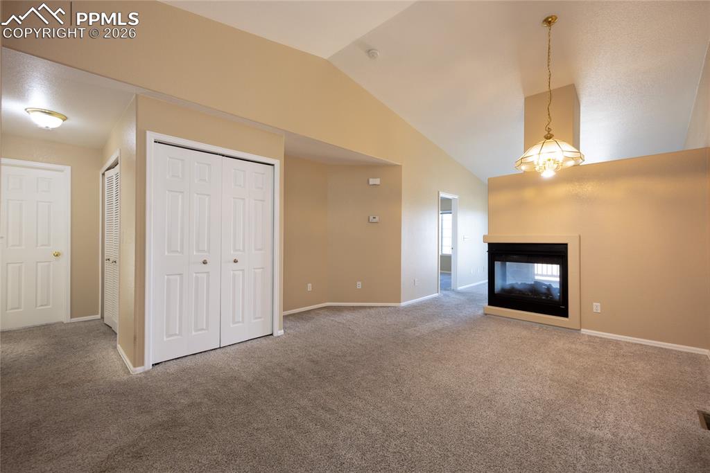 Image 5 of 25: Living area featuring a floor-to-ceiling fireplace, vaulted ceiling, and ca