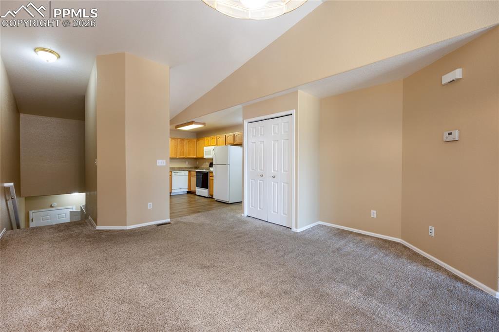 Image 7 of 25: Carpeted living area featuring neutral-toned walls, white bi-fold closet do