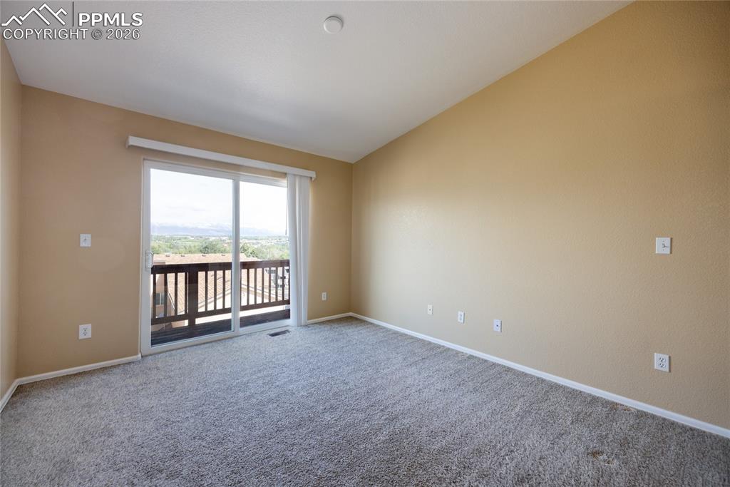 Image 8 of 25: Carpeted room featuring a sliding glass door opening to an outdoor balcony